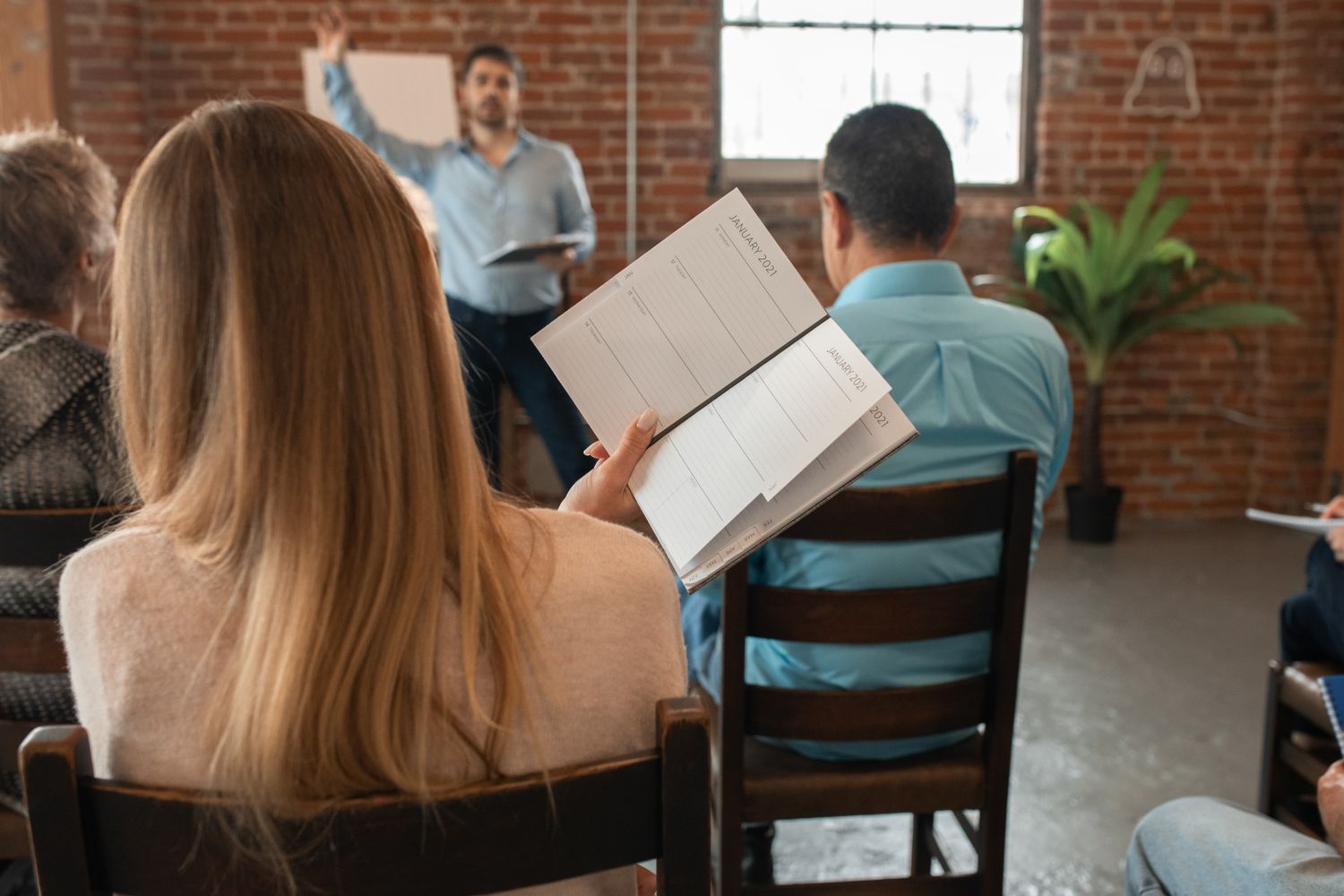 An adult classroom discussion, with a learner taking notes